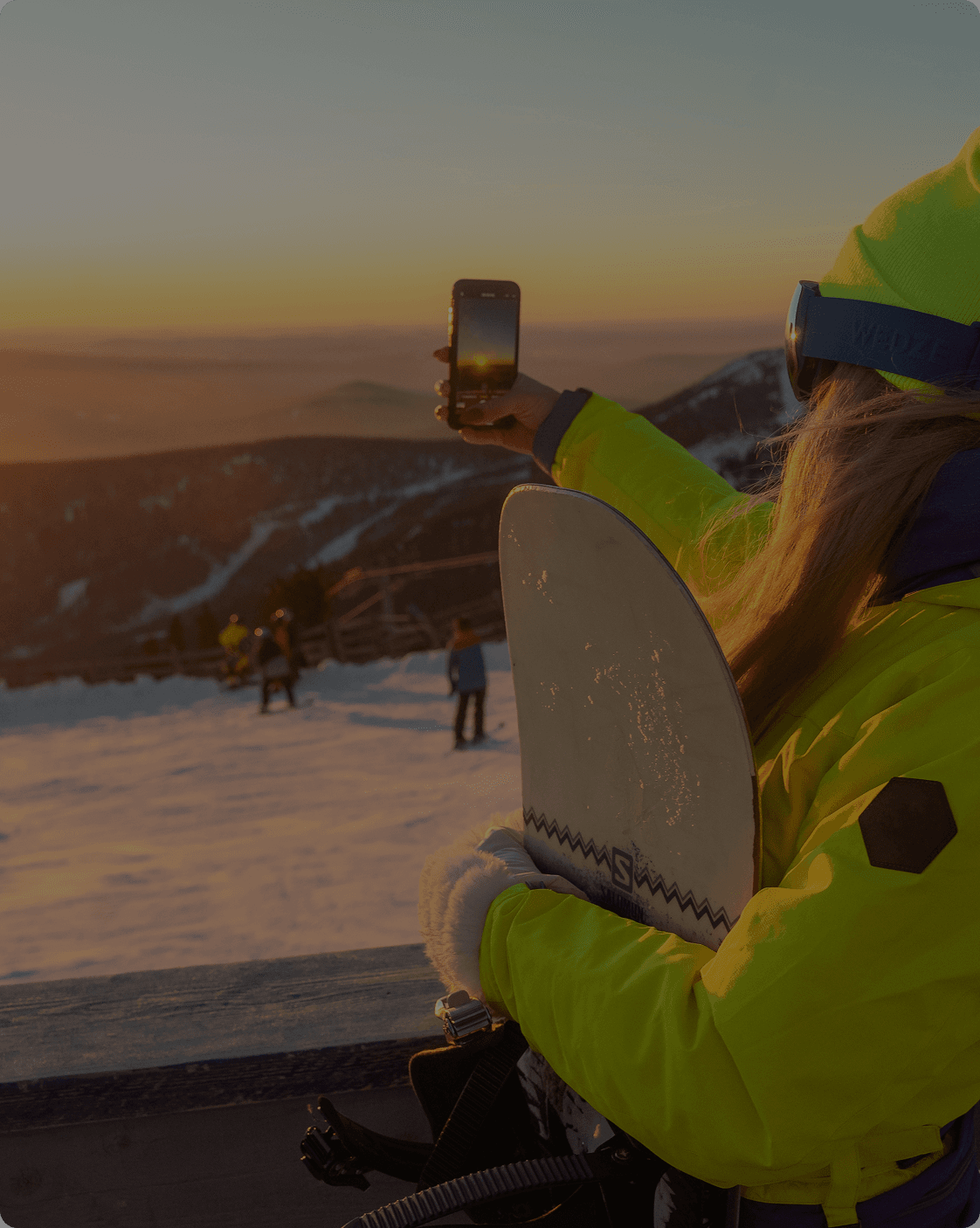 Woman taking a picture of the sunset in a ski slope